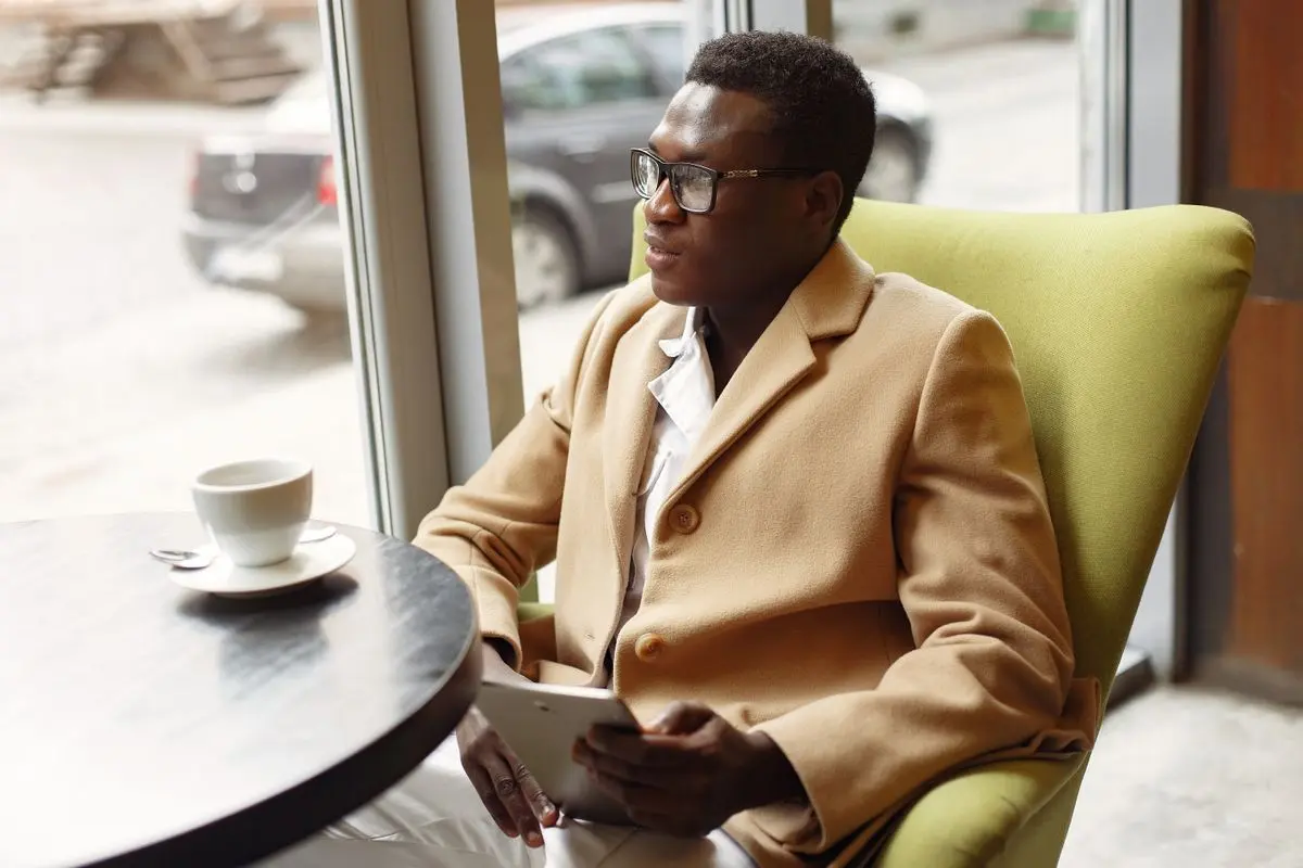 A business owner reads a drafted review reply on a tablet over coffee before deciding whether to approve it.